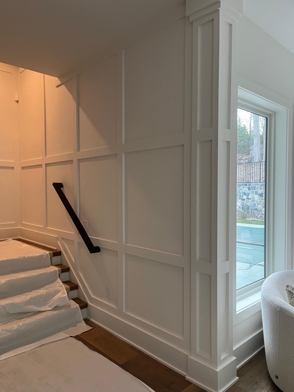 White decorative wall paneling and black stair rail