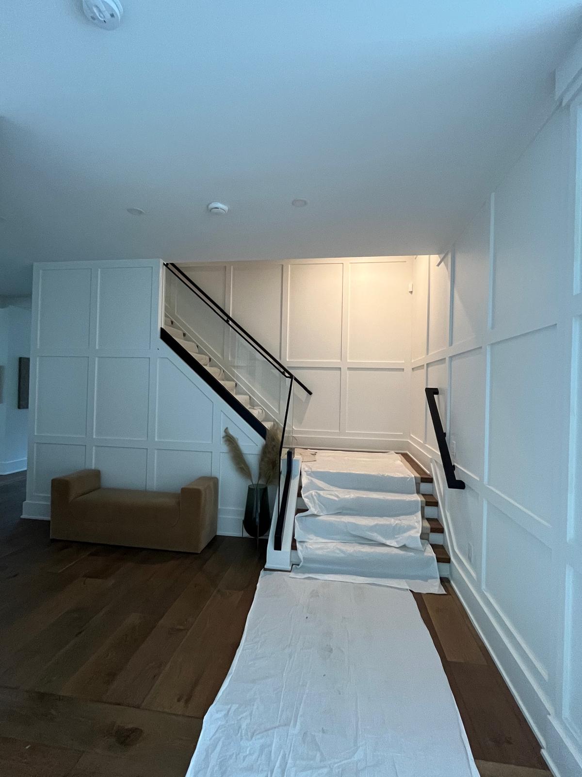 Wood flooring and white wall paneling around a staircase