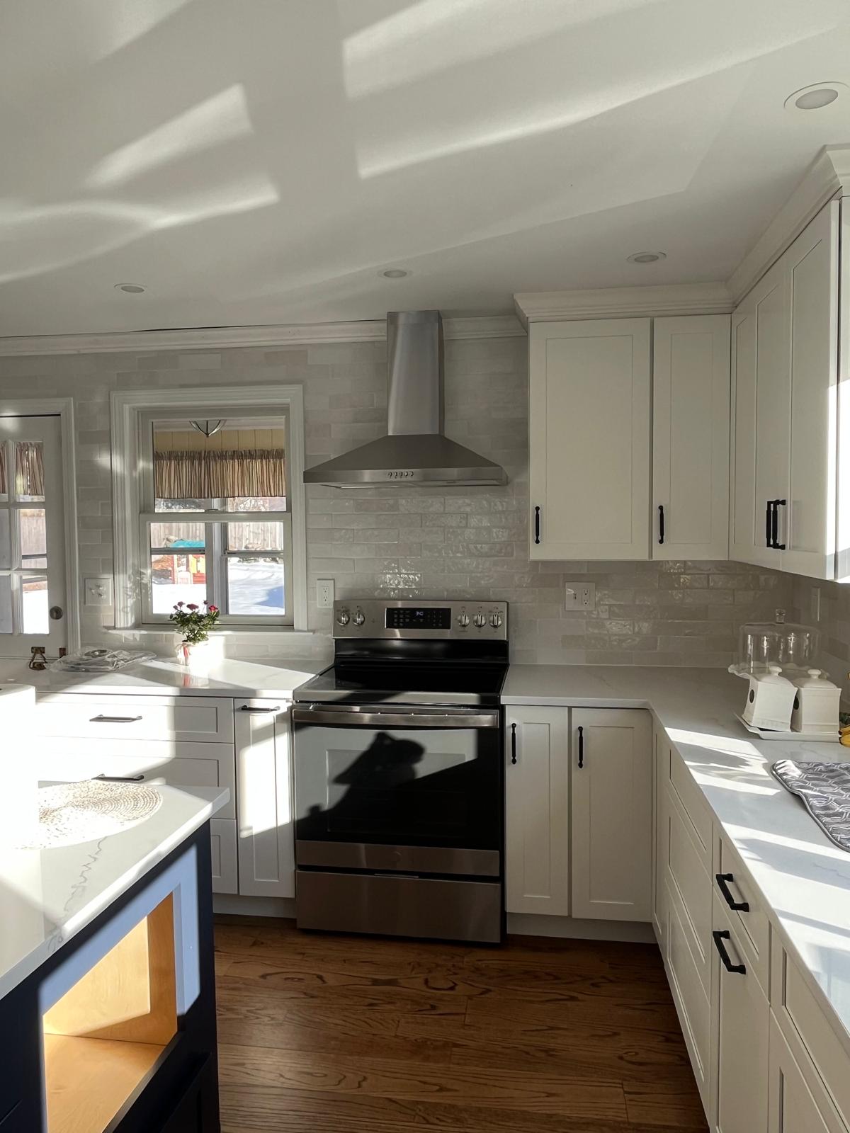 White kitchen with cabinetry, tile backsplash, and wood flooring